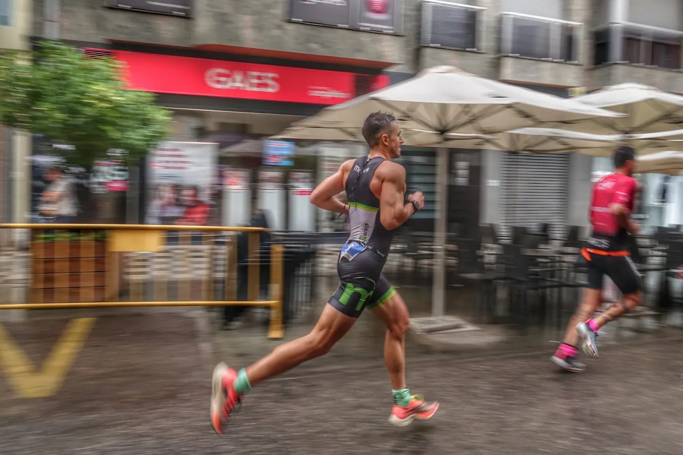Manuel running during a triathlon race on a wet city street