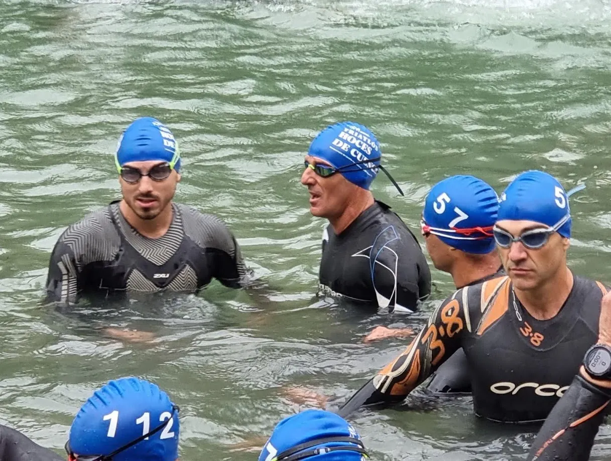 Manuel in a wetsuit and blue swim cap at an open-water triathlon start